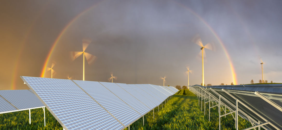 beautiful rainbow over a windmill farm and solar panels on a gre