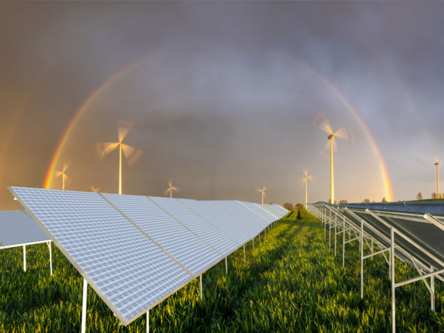 beautiful rainbow over a windmill farm and solar panels on a gre